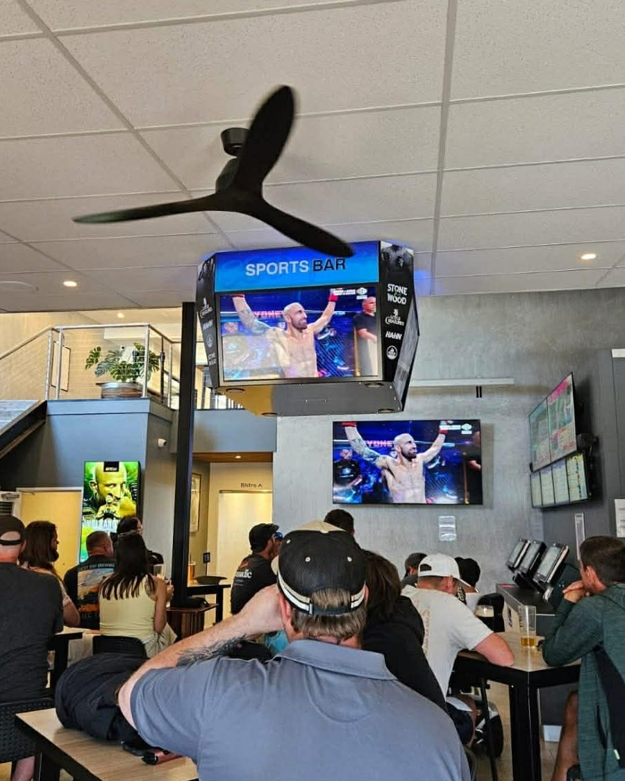 People in a sports bar watching Mini jumbotron with a sports event on the screen.